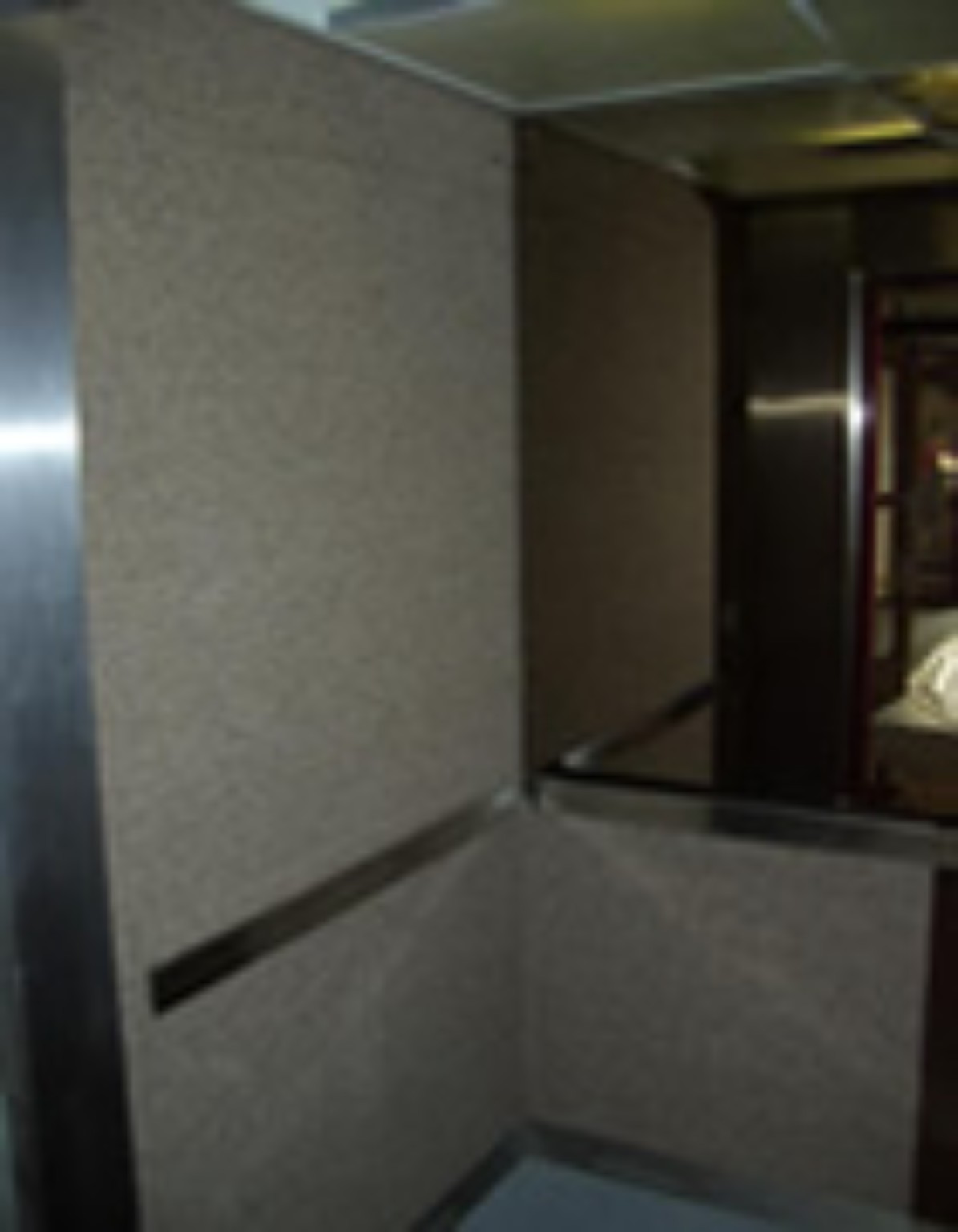 Lift interior before refurbishment, with older fabric-covered walls